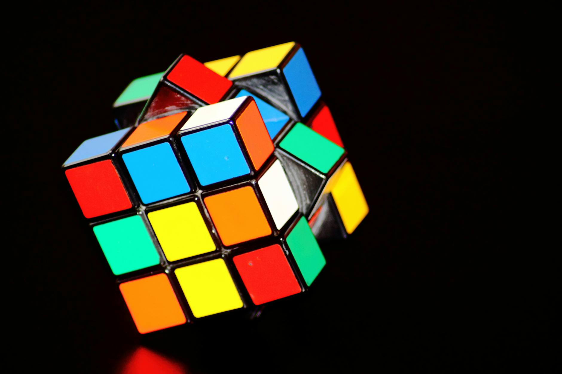 Close-up of a stylized geometric puzzle cube being solved by abstract hands.
